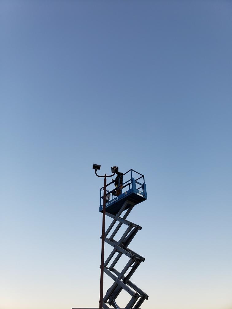 Facility technician on a lift to fix a light pole